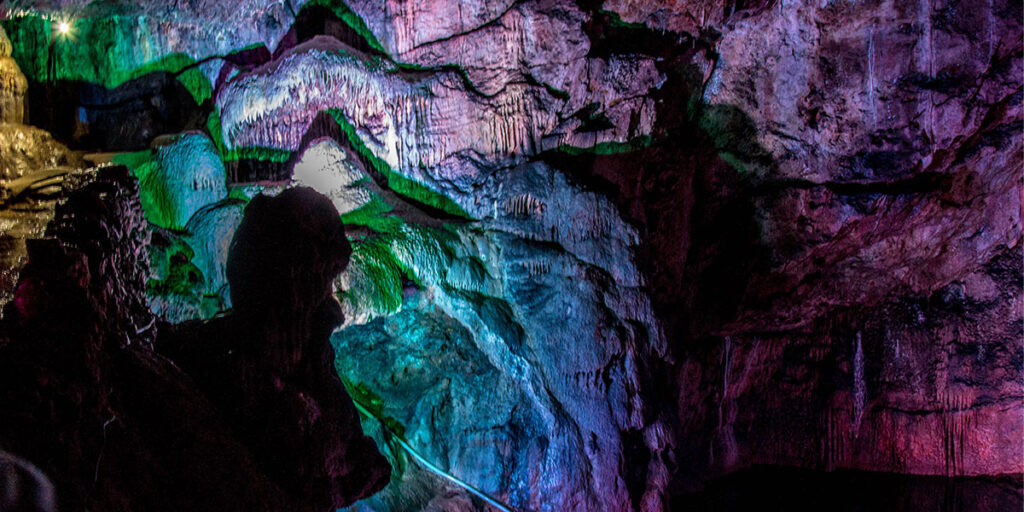 An underground cavern called the Witch's Kitchen lit up with different colours.