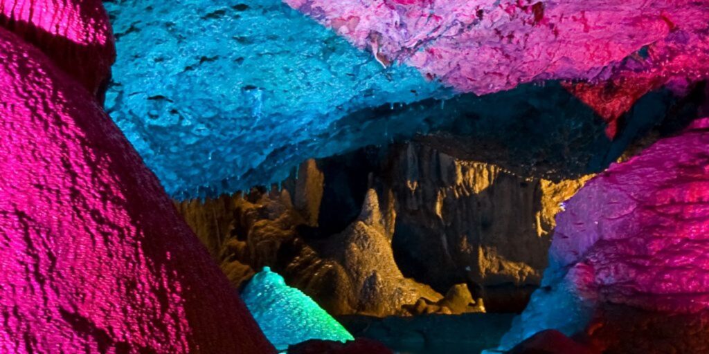 A close up of underground cavern walls lit up in blue, green and pink.