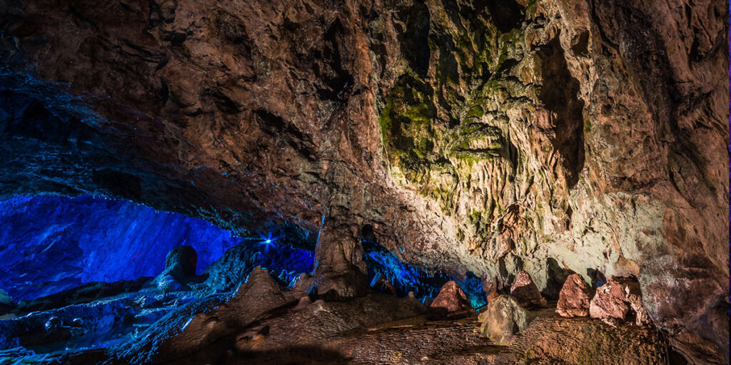 An underground cavern wall lit up in blue.