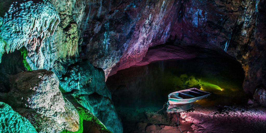 An underground lake in a cave with a boat on it.