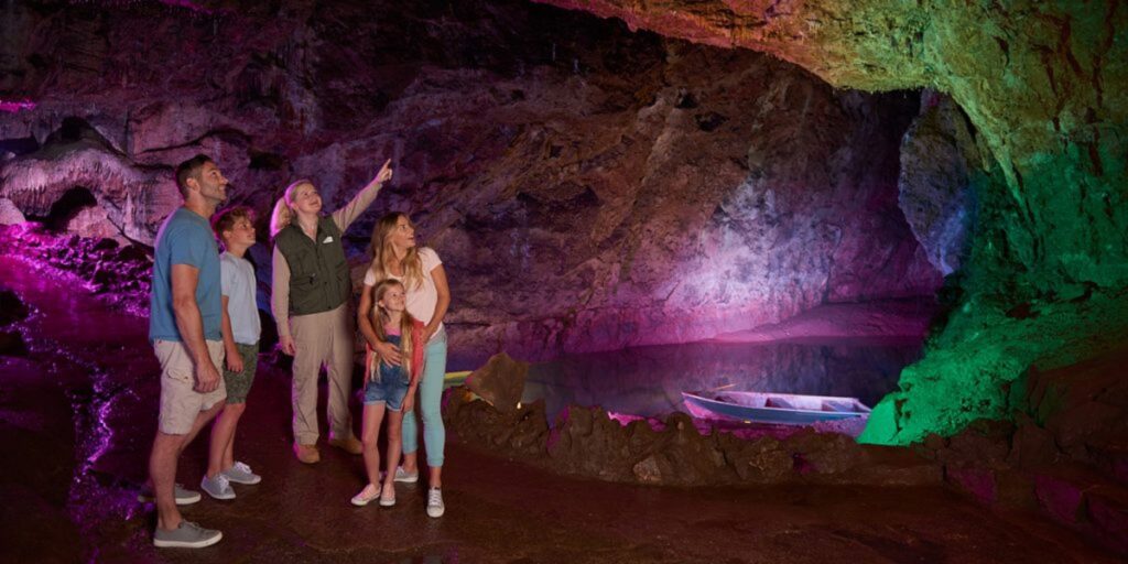 A family admires the features pointed out by a tour guide in a cave.