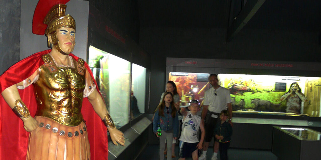A family in a museum with a model of a Roman centurion.