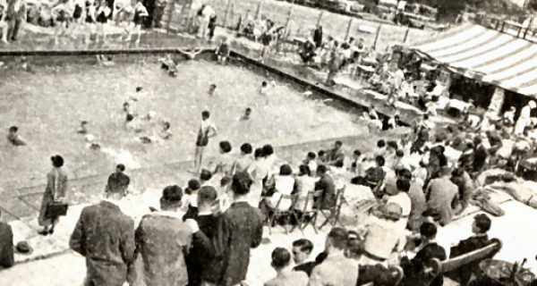 A black and white photo of inside a crowded swimming pool area.